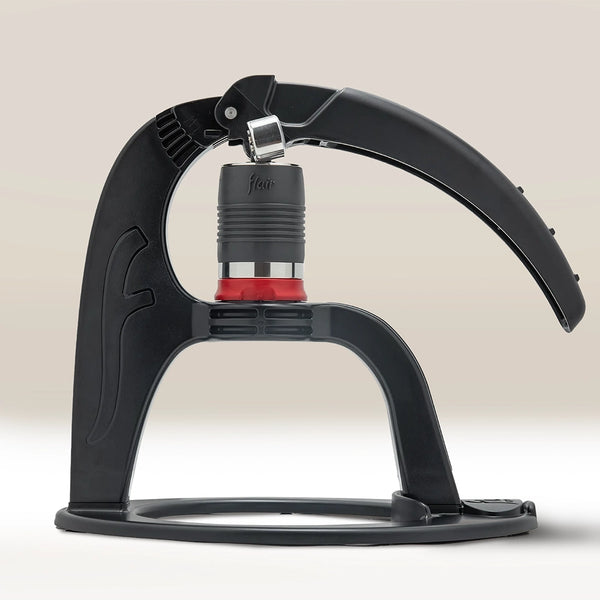 The Flair NEO Flex Espresso Maker by Flair, shown against a neutral background, features a black design with a curved lever arm, cylindrical brewing chamber, flow-control portafilter, and sturdy base—ideal for aspiring home baristas.