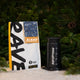 A bag of gourmet Christmas blend coffee next to an Aeropress Gift Set, set in front of pine branches and artificial snow.