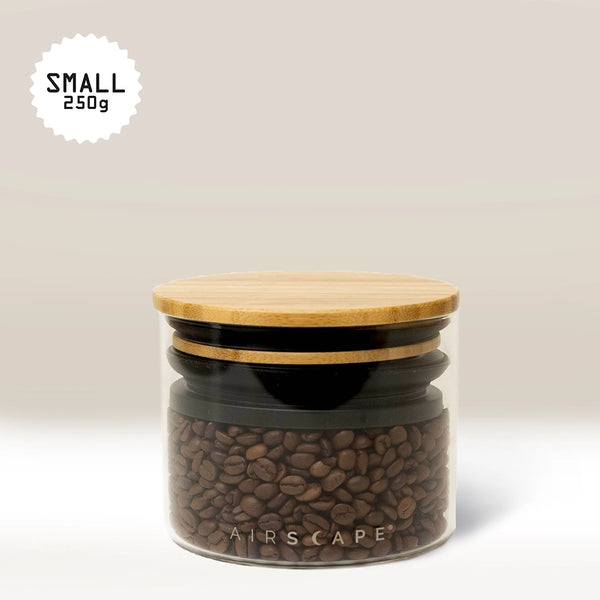 The Planetary Design Glass Airscape Coffee Storage Container, shown in clear glass with Airscape technology and a bamboo lid, holds coffee beans. "SMALL 250g" appears on a simple beige background.