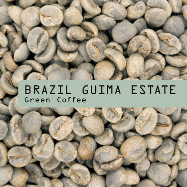 A close-up of unroasted Brazil Guima Estate Green Coffee Beans by RAVE COFFEE features a green label overlay stating the product name.