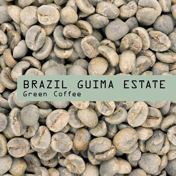 A close-up of unroasted Brazil Guima Estate Green Coffee Beans by RAVE COFFEE features a green label overlay stating the product name.