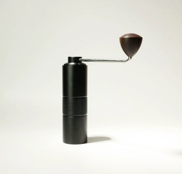 The AeroPress Gift Set with Grinder by Aeropress features a black manual coffee grinder with a textured grip and wooden-knob handle, ideal for grinding fresh beans for your AeroPress, shown upright against a plain white background.