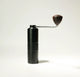 The AeroPress Gift Set with Grinder by Aeropress features a black manual coffee grinder with a textured grip and wooden-knob handle, ideal for grinding fresh beans for your AeroPress, shown upright against a plain white background.