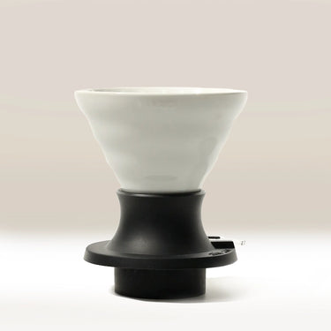 The Hario Switch V60 Ceramic Immersion Dripper (Size 02) features a white fluted ceramic design atop a black plastic base, showcasing Hario’s signature V60 style against a neutral background.