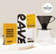 The Hario Hand Brewed Coffee Gift Set by Hario includes coffee beans, a yellow brew guide, white cone filters, and a black V60 dripper on a clear glass carafe—all you need for pour-over coffee.