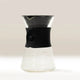 The Hario V60 Drip Decanter by Hario features a black silicone grip, wide spout, and curvy borosilicate glass base, showcasing a modern minimalist design on a neutral background.
