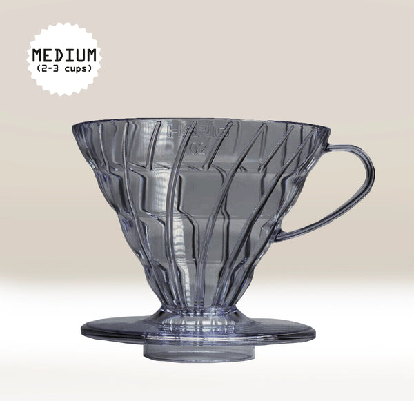 Black, semi-transparent plastic coffee filter with handle on a light beige background