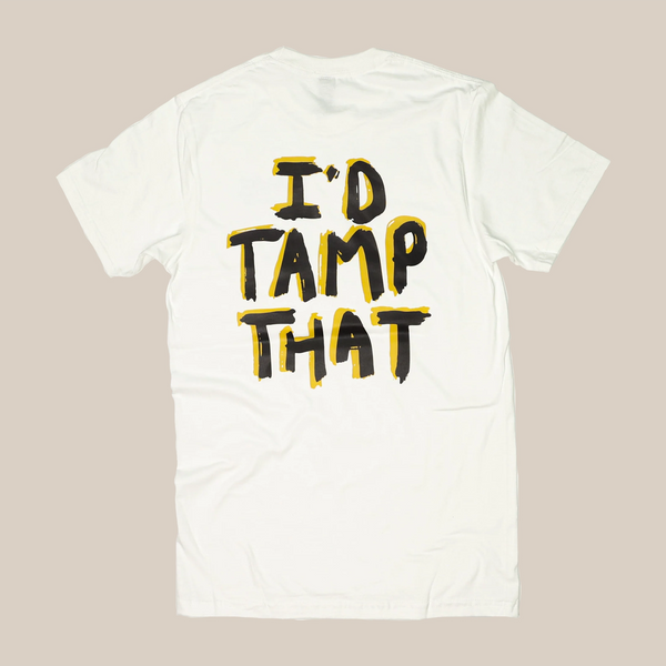 The I’d Tamp That T-Shirt by RAVE COFFEE is a white unisex cotton tee featuring "ID TAMP THAT" in large, bold black letters, outlined in yellow, printed on the back.