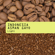 Coffee beans and ground coffee split horizontally, with a bright yellow-green label across the center reading 'INDONESIA ASMAN GAYO Light'.