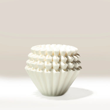 A stack of Kalita Wave 185 Paper Filters (Pack of 100) by Kalita, arranged neatly on a light surface with a beige background—ideal for flat bottom brewers.