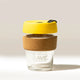 The KeepCup Rave Coffee Glass KeepCup features tempered glass, a cork band, yellow lid, and black plug. 