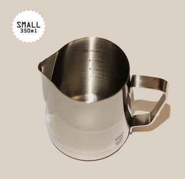 The Crema Pro Milk Steaming Jug or Pitcher, 12 OZ/350ml, features stainless steel construction, a handle, internal measurement markings, and a spout. 