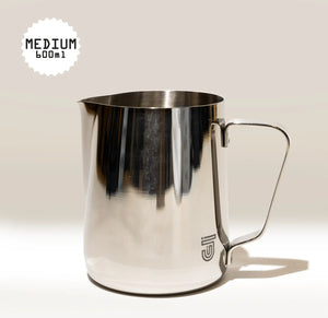 The Crema Pro Milk Steaming Jug, 20 OZ / 600ml, features a shiny stainless steel design with handle and small logo near the base. Perfect for latte art, it sits on a neutral background with "MEDIUM 600ml" capacity label.