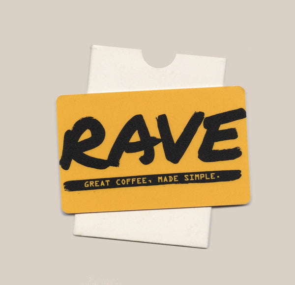 A vibrant yellow Coffee E-gift Card from Gift Card, featuring bold black “RAVE” text and the phrase “Great coffee, made simple.” beneath it, is displayed atop a partially visible white envelope—ideal for gifting coffee lovers.
