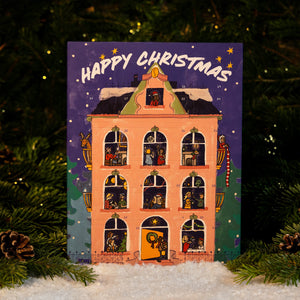 RAVE COFFEE Coffee Chocolate Advent Calendar illustrated as a multi-story house containing coffee and handmade chocolates, set against a backdrop of pine branches and snow.