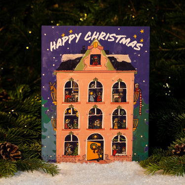 RAVE COFFEE Coffee Chocolate Advent Calendar illustrated as a multi-story house containing coffee and handmade chocolates, set against a backdrop of pine branches and snow.