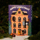 A RAVE COFFEE Coffee Chocolate Advent Calendar featuring an illustration of a festive house with numbered windows, set against a backdrop of pine branches and snow.
