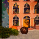 A handmade chocolate truffle sits on a bed of artificial snow next to a pine branch in front of a RAVE COFFEE Coffee Chocolate Advent Calendar depicting a festive house.