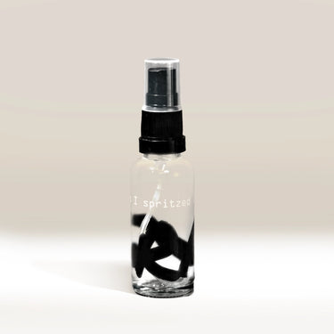 The RDT Bottle (Oops I Spritzed it Again) is a clear glass spray bottle with a black pump and quirky 