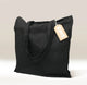 A black Cafe Gift Bag with two handles stands upright. A brown tag reading 
