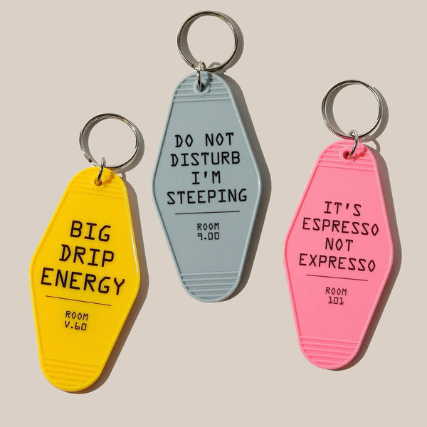 Three RAVE Coffee Rave Keyrings: yellow with "BIG DRIP ENERGY," gray with "DO NOT DISTURB I’M STEEPING," and pink with "IT’S ESPRESSO NOT EXPRESSO." Each features a cool vintage motel design and a small room number at the bottom.