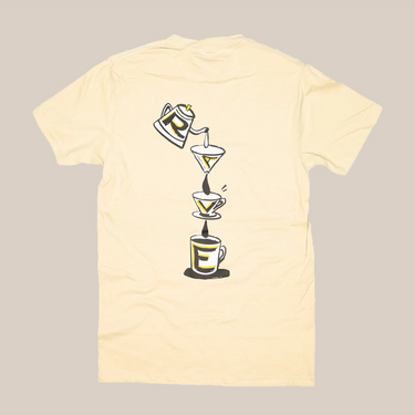 The Rave V60 T-Shirt by RAVE COFFEE is a cream unisex cotton tee with a back print of a coffee pot pouring into two filters and a cup, forming the word 
