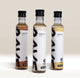 RAVE COFFEE Best Selling Syrup Set featuring three glass bottles of flavored coffee syrups labeled hazelnut, vanilla, and caramel.