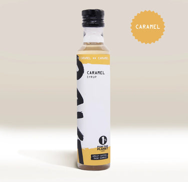 A bottle of RAVE COFFEE Rave Coffee Syrups in caramel flavour, featuring a black cap and yellow label, sits on a light background. A round badge to the right reads CARAMEL. Perfect for enhancing your favourite drinks, this UK-blended coffee syrup from RAVE COFFEE also displays the 1% for the Planet logo on the front.