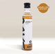 A clear bottle of RAVE COFFEE’s Rave Coffee Syrups in Caramelised Biscuit flavour, featuring a black cap, white label with brown accents, and prominent text and badge reading “Caramelised Biscuit.” This UK-made flavoured coffee syrup is displayed against a light beige background.