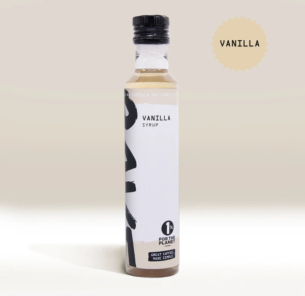 A bottle of RAVE COFFEE’s Rave Coffee Syrups with a black cap, labeled Vanilla Syrup and 1% For The Planet—ideal for enhancing your favourite coffee or flavour syrup creations. A beige circle with “Vanilla” appears in the upper right corner against a neutral background. Proudly UK blended by RAVE COFFEE for quality and taste.
