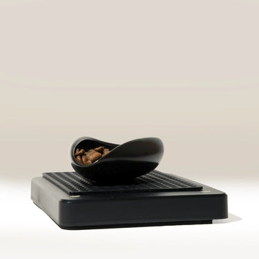 Black coffee doser on digital scales with a neutral background