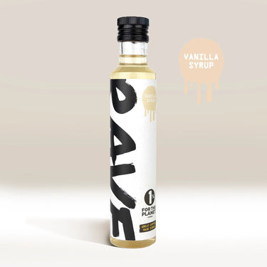 A clear glass bottle labeled RAVE COFFEE contains Rave Coffee Syrups—ideal for coffee syrup lovers. The label reads 1% For The Planet and Vanilla Syrup, with a beige swatch and the text Vanilla Syrup in the background.
