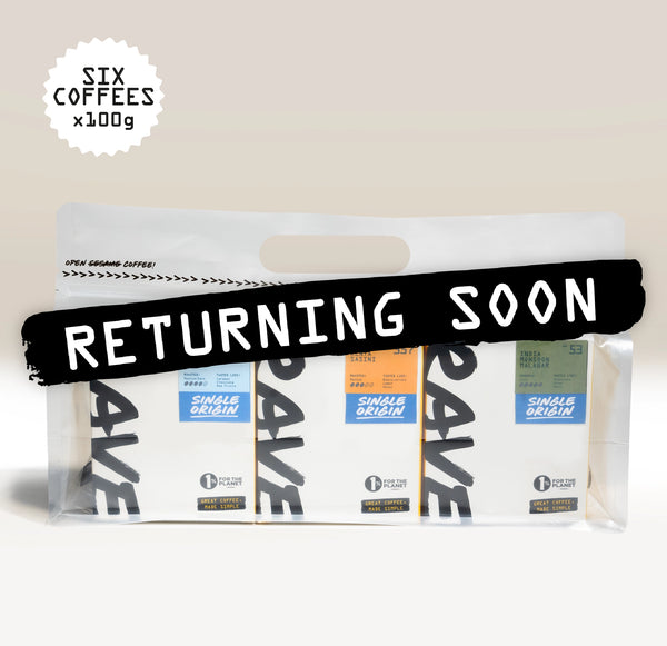 A clear plastic bag holding three coffee pouches with a large black banner across the front reading 'RETURNING SOON' in white text. A white scalloped badge in the upper left says 'SIX COFFEES x100g'.