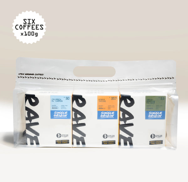 A clear bag displays six boxes of Ravecoffee’s Best Selling Single Origins - Whole Bean Variety Pack. Each box, with its own distinct colored label highlighting unique coffee details, offers a vibrant assortment of single-origin coffees. At the top left, text reads SIX COFFEES x 100g against a soft light gradient background.