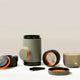 A WACACO Minipresso GR2 travel coffee maker with detachable cup, filters, lids, and brush is neatly arranged on a light surface against a neutral background.