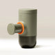 The WACACO Minipresso GR2, a compact cylindrical portable espresso maker in matte gray with an orange accent ring and plunger handle, stands upright on a neutral background.