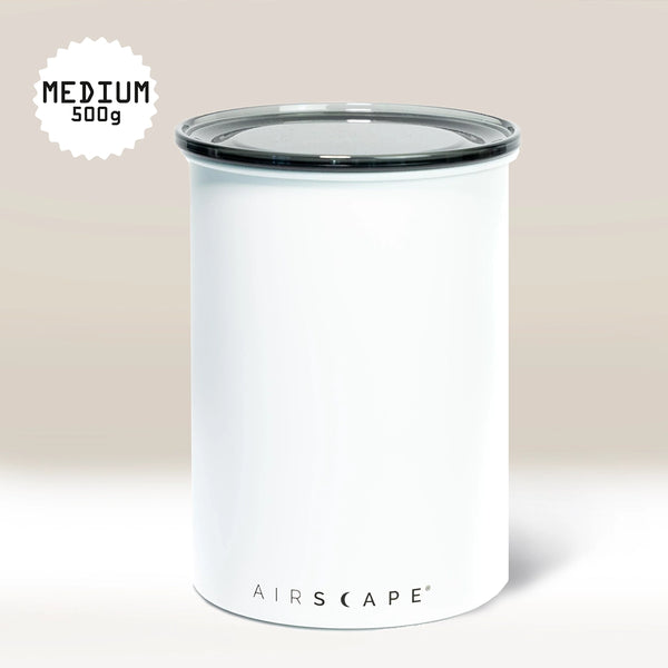 A White Airscape Coffee Storage Container by Planetary Design sits on a white surface. Its clear, oxygen-removing lid is labeled AIRSCAPE. A top left badge reads MEDIUM 500g in black text.
