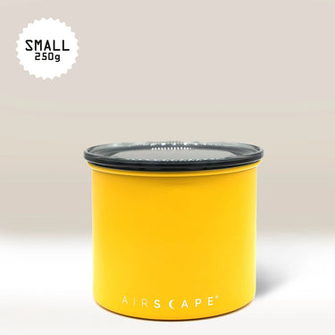 The Planetary Design Yellow Airscape Coffee Storage Container with oxygen removal tech and a black lid sits on a neutral background. A white starburst in the top left corner reads 