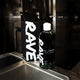 A bottle of RAVE COFFEE Coffee Liqueur stands on a metal countertop next to its black box, both with bold white text, set against a blurred industrial background.