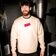 Man wearing a beige sweatshirt with a pink bourbon in a roastery setting